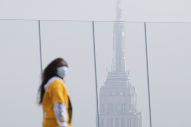 A sightseer wears a face mask with a view of the Empire State Building while touring the Edge observation and outdoor sky deck in Hudson Yards.